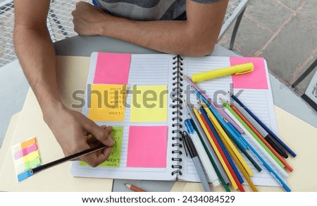Student writing in a notebook and making notes on post its