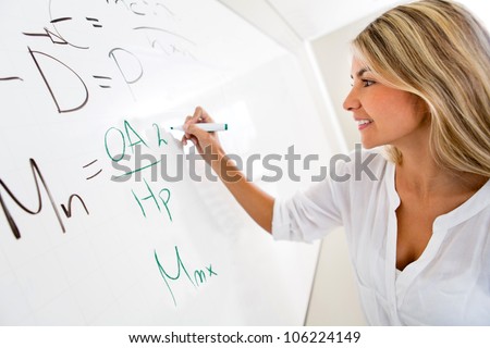 Student writing on the board the solution to an equation