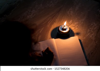 A Student Writing On Notebook In A Kerosene Oil Lamp 