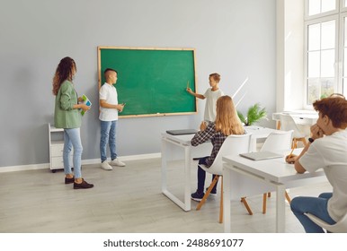 Students answering questions at the chalkboard during a lesson with their teacher in a school classroom. The group is actively engaged in learning, emphasizing education and participation. - Powered by Shutterstock