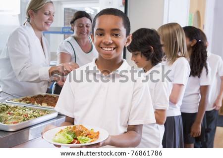 Students in cafeteria line with one holding his healthy meal and looking at camera