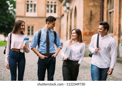 Students in campus communacating, laughing. Group of college friends showing positive emotions, holding books. - Shutterstock ID 1122349730