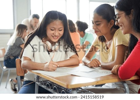 Students in class doing a team project sitting together in class. Asian, Caucasian and Latina.