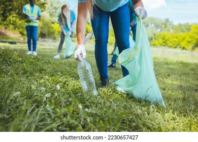 Students clean the local park, collect garbage in bags. On a beautiful sunny day, a group of young volunteers collect garbage in nature. Focus in foreground - Powered by Shutterstock