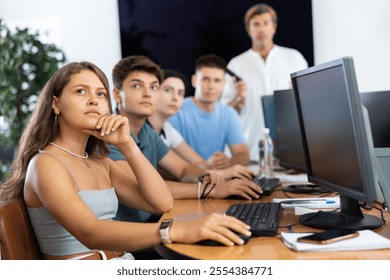 Students of data science courses sit in class near computers, watch to teacher and listen attentively to lecturer. Modern IT profession, retraining, advanced training
