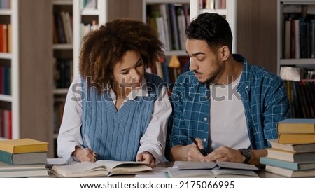 Students do homework in library teamwork working on joint project cute girl explaining task to male friend write notes preparing for exam communicate rejoice in achievement successful cooperation