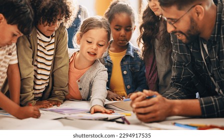 Students doing a creativity project with their teacher in a classroom. Group of primary school children learning how to draw and colour with the help of their educator. - Powered by Shutterstock