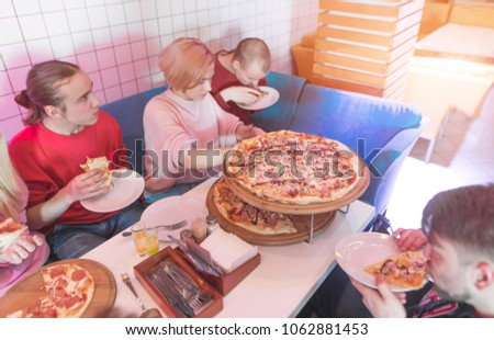 Students eat a great appetizer pizza in a cozy restaurant. A group of young people eating pizza in a pizzeria. Lunch with friends and pizza