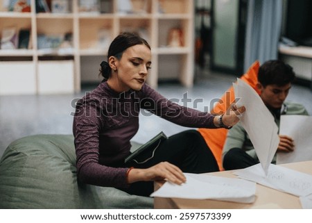 Students engaged in collaborative work in a modern educational space, reviewing notes and discussing classwork on a university campus.