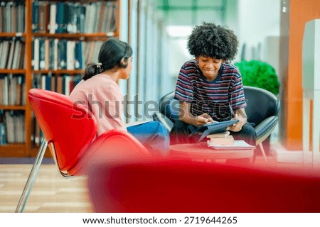 Students engaged in group study discussion in library using tablet representing cooperative learning academic growth education lifestyle.