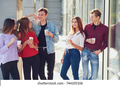 Students enjoying cup of coffee to go on street. Young people communicating outdoor at morning with cup of energy drink - Shutterstock ID 744105106