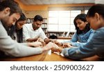 Students, group and praying together for study, faith and university exam with people in library. Friends, diversity and holding hands on campus for college, education and Christian society community