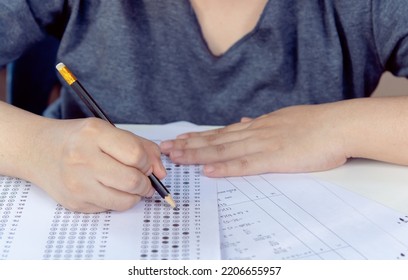 Students Hand Holding Pencil Writing Selected Choice On Answer Sheets And Mathematics Question Sheets. Students Testing Doing Examination. School Exam