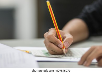 students hand testing doing examination with pencil drawing selected choice on answer sheets in school exam at  college