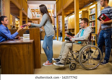 Students With Handicapped Man In Row At The Counter In College Library