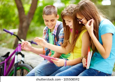 Students Hanging Out Together Watching Funny Staff On The Screen Of The Tablet Computer