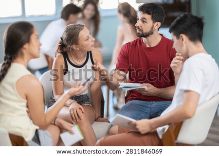 Students have divided into two teams and are discussing tactics of debate or competition. Members of two teams sit in circle and debate. Processing of discuss, debate, consult and prepare speech
