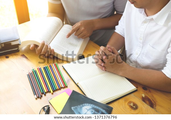Students helps friend teaching and\
learning subject additional in library. Education\
concept.