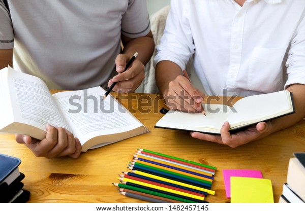 Students helps friend teaching and\
learning subject additional in library. Education\
concept.
