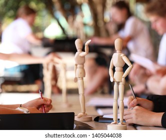 Students At High School Outside Drawing Wooden Manikins For Visual Art Class Lesson. Artists Training And Learning To Draw Human Figure Studies. 