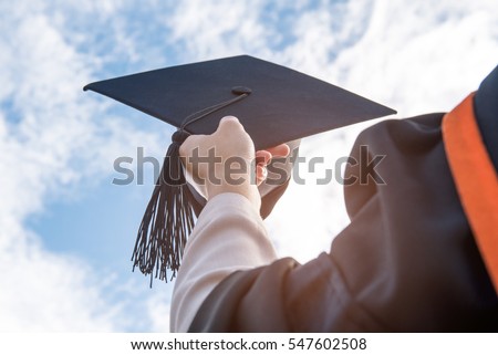 The students holding a shot of graduation cap by their hand in a bright sky during ceremony success graduates at the University, Concept of Successful Education in Hight School,Congratulated Degree 