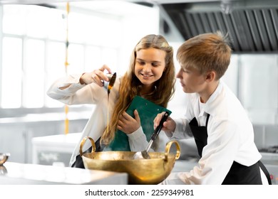 Students are learning to cook in a culinary institute with a standard kitchen and complete equipment. And have a professional chef as a trainer. - Shutterstock ID 2259349981