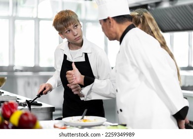 Students are learning to cook in a culinary institute with a standard kitchen and complete equipment. And have a professional chef as a trainer. - Shutterstock ID 2259349989