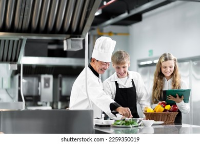 Students are learning to cook in a culinary institute with a standard kitchen and complete equipment. And have a professional chef as a trainer. - Shutterstock ID 2259350019