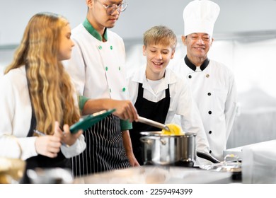 Students are learning to cook in a culinary institute with a standard kitchen and complete equipment. And have a professional chef as a trainer. - Shutterstock ID 2259494399