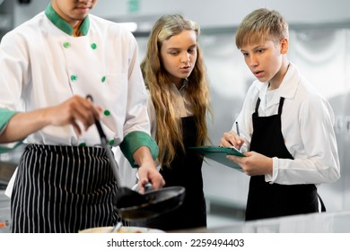 Students are learning to cook in a culinary institute with a standard kitchen and complete equipment. And have a professional chef as a trainer. - Shutterstock ID 2259494403