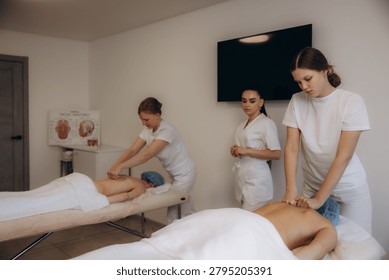 Students learning and practicing massage therapy techniques on clients under instructor supervision during a professional training course