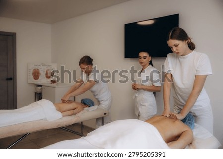Students learning and practicing massage therapy techniques on clients under instructor supervision during a professional training course
