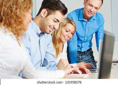 Studierende, die zusammen mit Lehrer und Laptop-Computer studieren