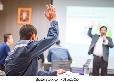 Students Lifting Hands In College Class With Teacher 