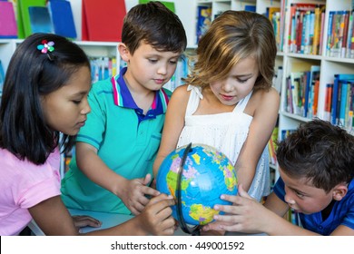 Students looking at globe while sitting in school library