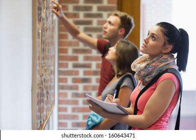 Students Looking At Notice Board In College