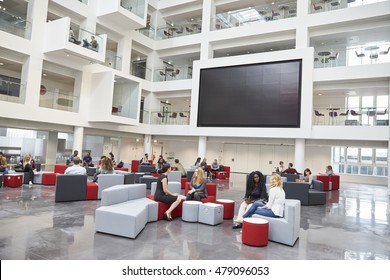 Students meeting in front of screen in atrium at university