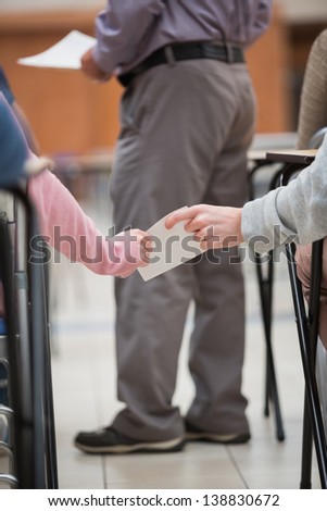 Students passing a note behind the back of the teacher while being in the classroom