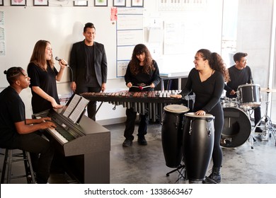 Students At Performing Arts School Playing In Band At Rehearsal With Teacher