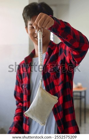 students are performing a physics experiment on the weight of objects using a spring balance. Concept of science classroom, learning science, science skills, learning,science experiment and physics.  