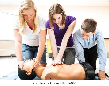 Students practicing CPR life saving techniques on a mannequin. - Powered by Shutterstock