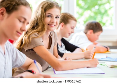 Students or pupils of school class writing an exam test in classroom concentrating on their work