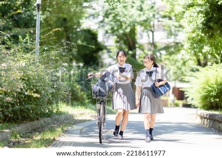 Students pushing bicycles and walking in the park