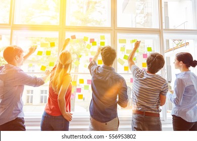 Students putting sticky notes on window for planning analysis - Shutterstock ID 556953802