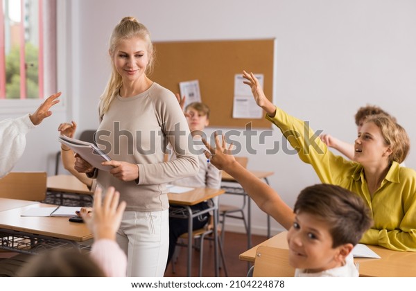Students raise their hand to answer during a lesson\
in class