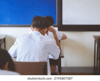 Students reading exam answer sheets exercises in classroom of school with headache and stress