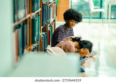 Students reading textbook inside library aisle showing cooperative study routine academic concentration self learning environment higher education.