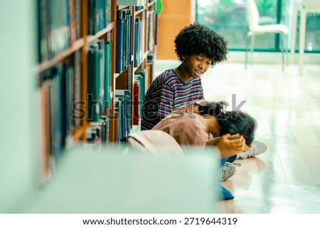 Students reading textbook inside library aisle showing cooperative study routine academic concentration self learning environment higher education.