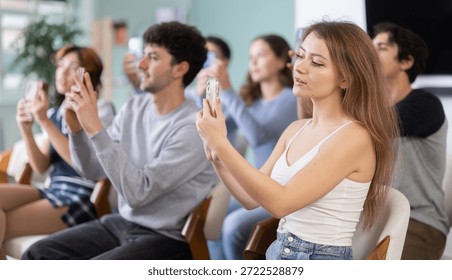 Students scan QR code and use their phone to connect to schools online group. Lecture room is filled with listeners. Company managers during training, professional development courses