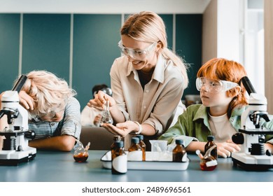 Students schoolchildren kids pupils making experiments with teacher using flasks with reagents at chemistry science lesson class at school lab - Powered by Shutterstock